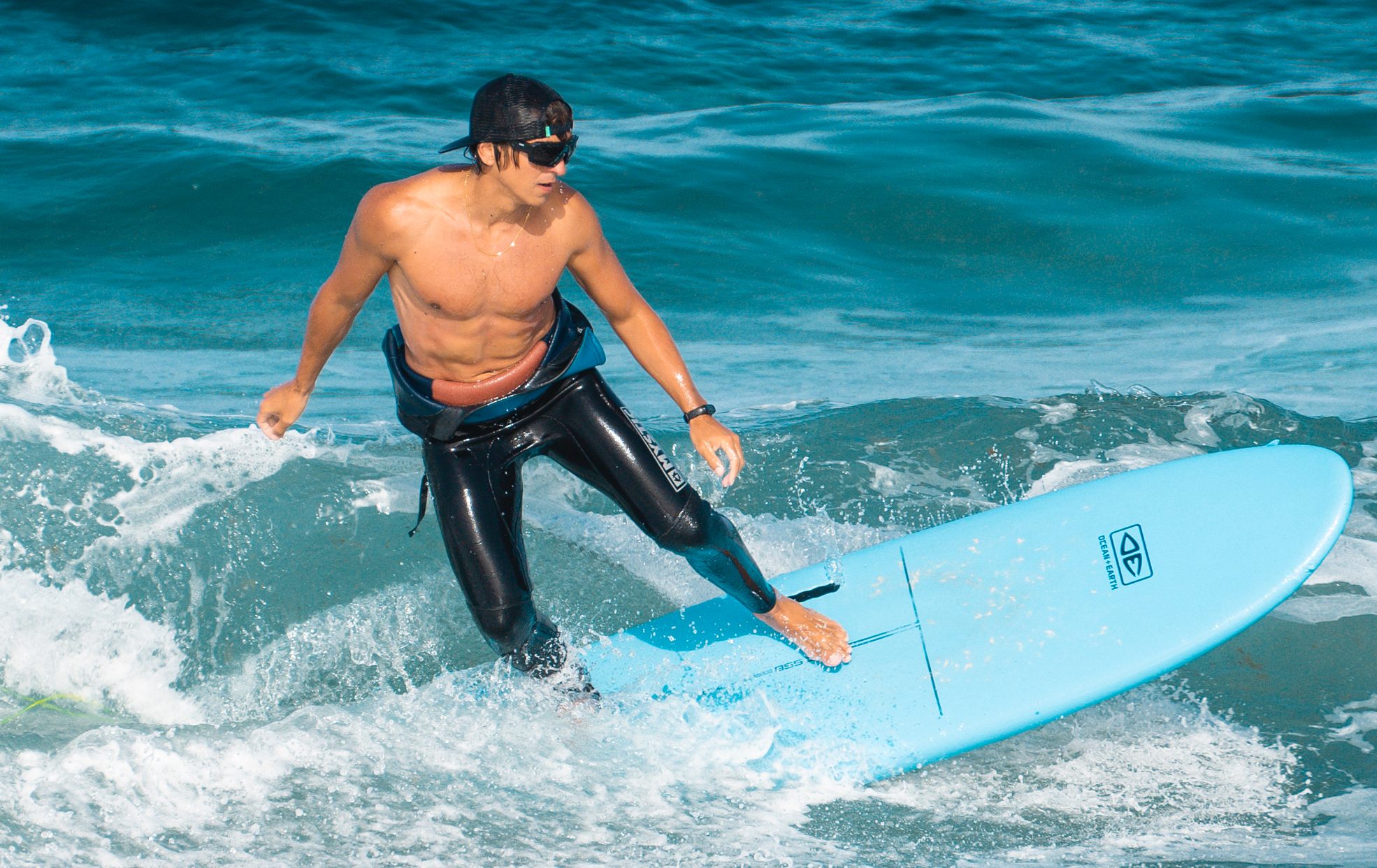 Surfer mit Neoprenanzug reitet eine Welle - Redshark